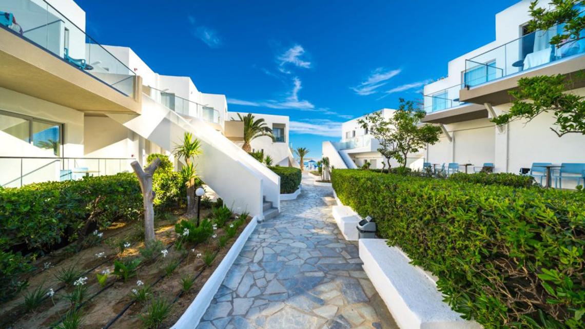 Foto des Eingangsbereichs des Adele Beach Hotels mit weißen Gebäuden und Gehweg