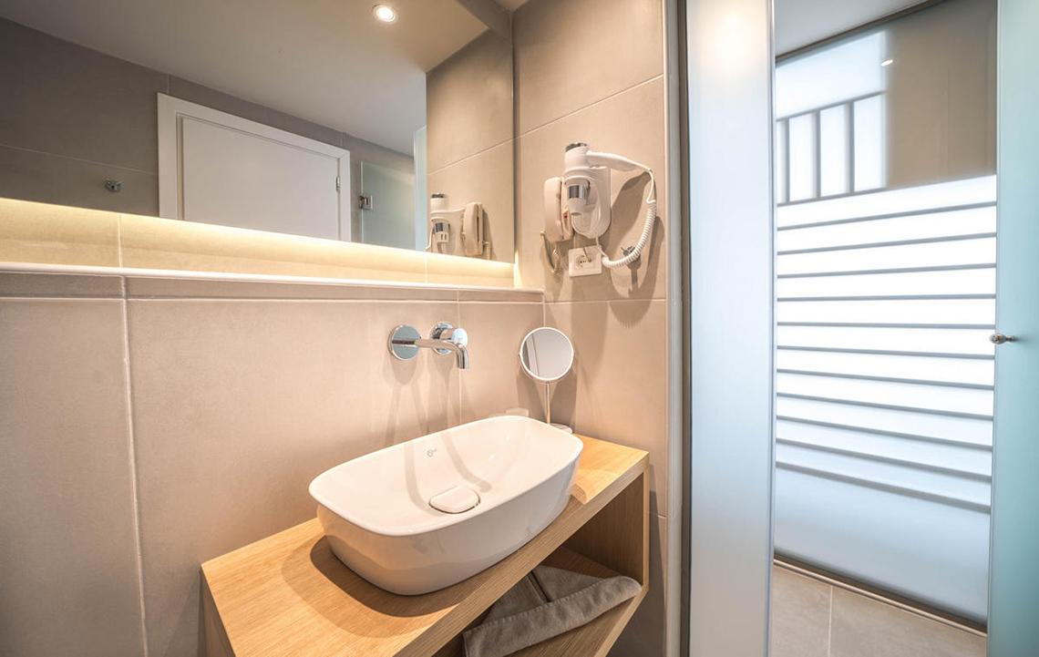 Badezimmer im Adele Beach Hotel mit Waschbecken, Spiegel und Föhn