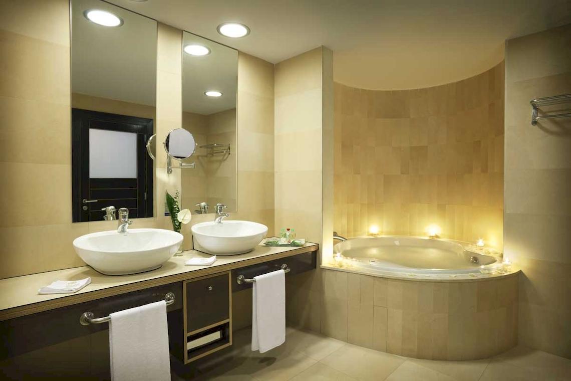 Badezimmer im Roca Nivaria Gran Hotel mit zwei Waschbecken, Spiegel und Badewanne mit Kerzen.