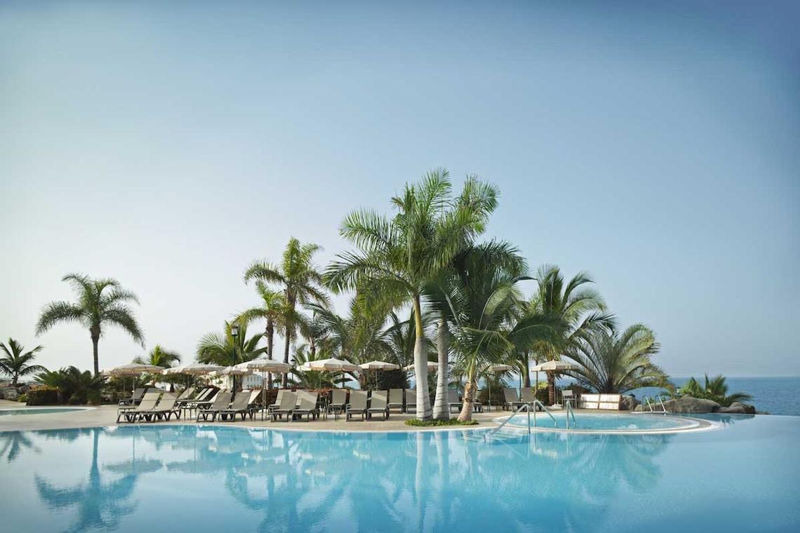 Der Pool des Roca Nivaria Gran Hotel mit Palmen und Sonnenschirmen.
