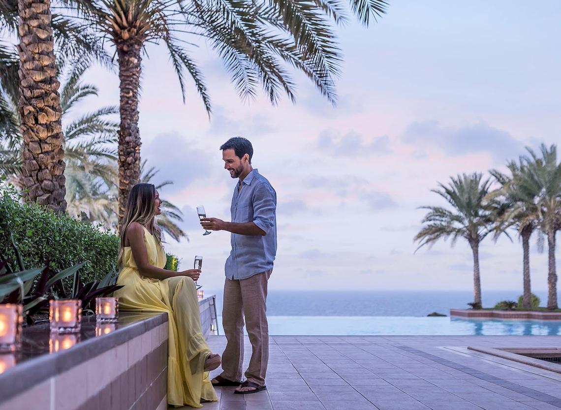 Paar mit Sektgläsern vor dem Pool im Shangri-La Al Husn Resort & Spa