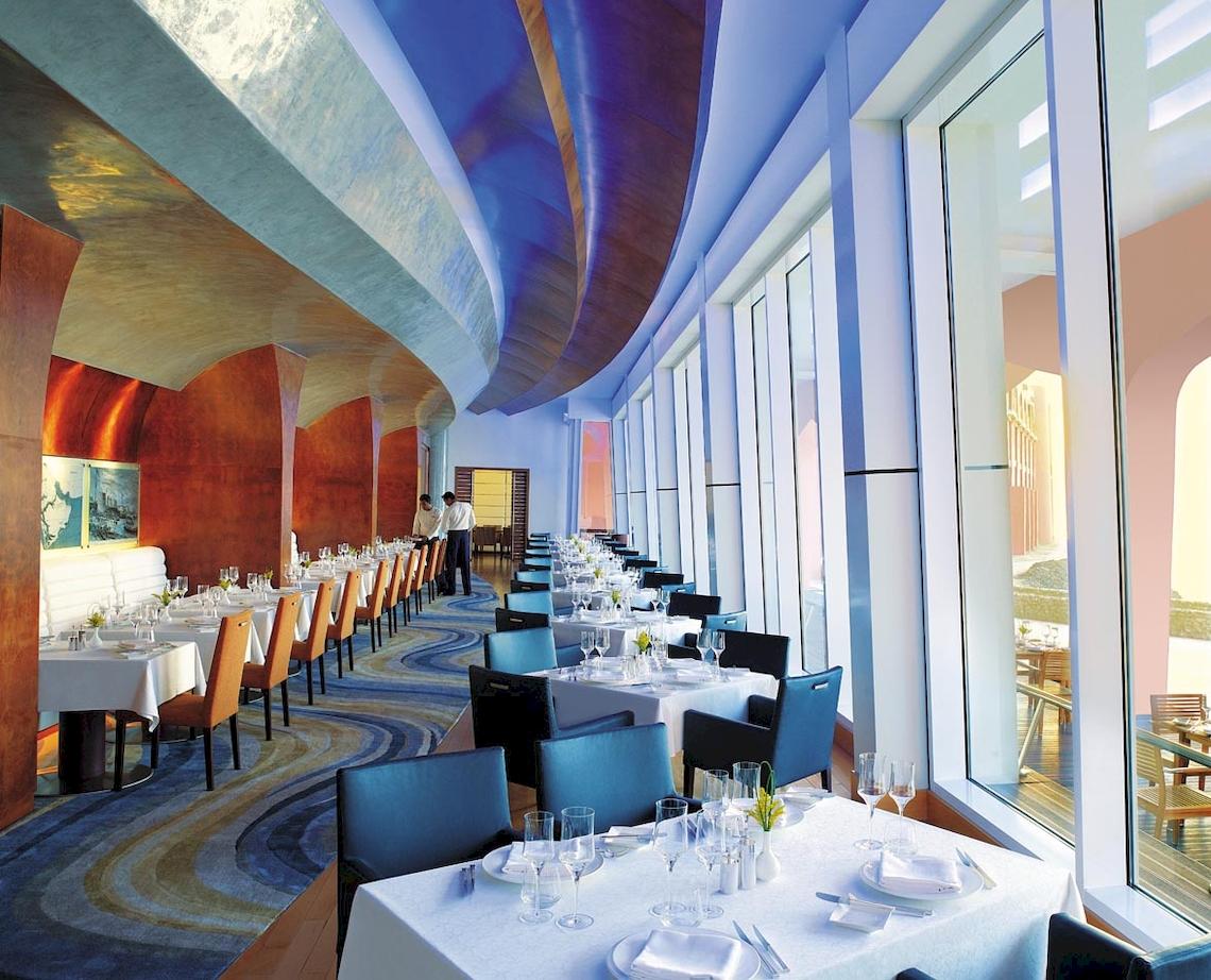 Restaurant im Shangri-La Al Husn Resort & Spa mit gedeckten Tischen und Blick auf die Außenterrasse.
