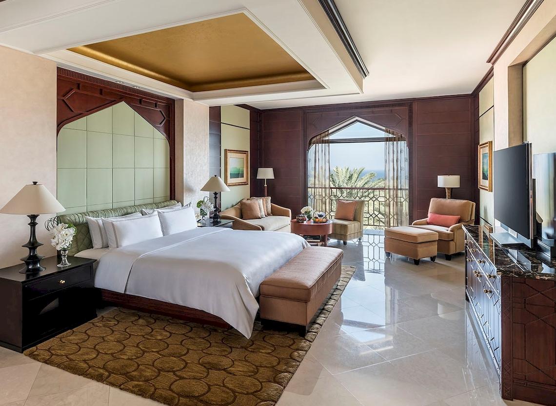Luxus Schlafzimmer im Shangri-La Al Husn Resort & Spa mit großem Bett, Sitzbereich und Blick auf das Meer.