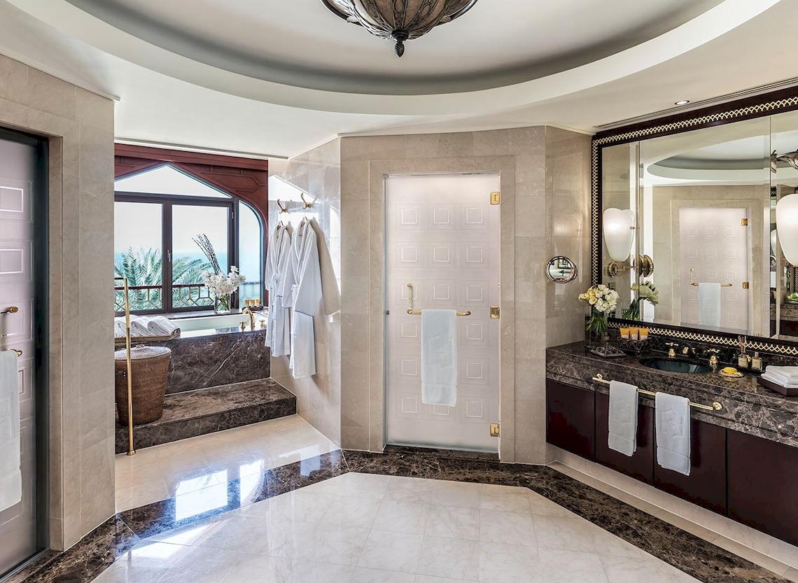 Luxuriöses Badezimmer im Shangri-La Al Husn Resort & Spa mit Badewanne, Waschbecken und Spiegel.