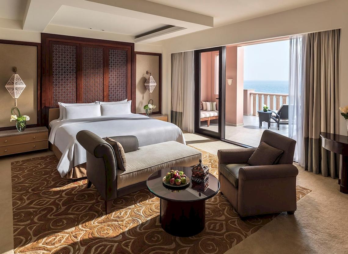Hotelzimmer im Shangri-La Al Husn Resort & Spa mit Bett, Couch, Tisch und Balkon.