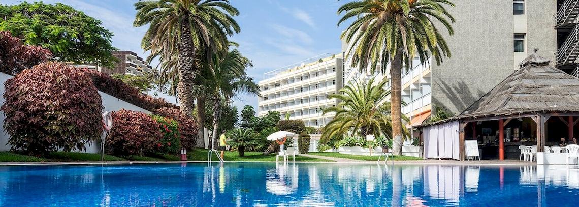 Der Poolbereich des Bluesea Interpalace Hotels mit Palmen und Gebäuden im Hintergrund.