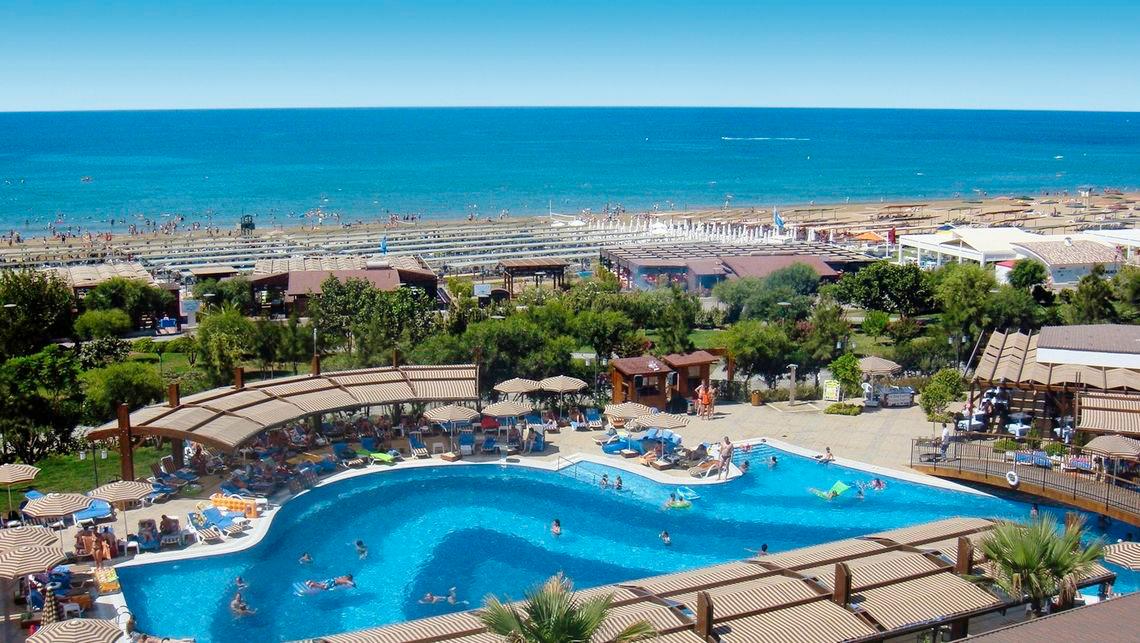 Hotelpool mit Blick auf das Meer und den Strand, viele Gäste genießen den Pool.