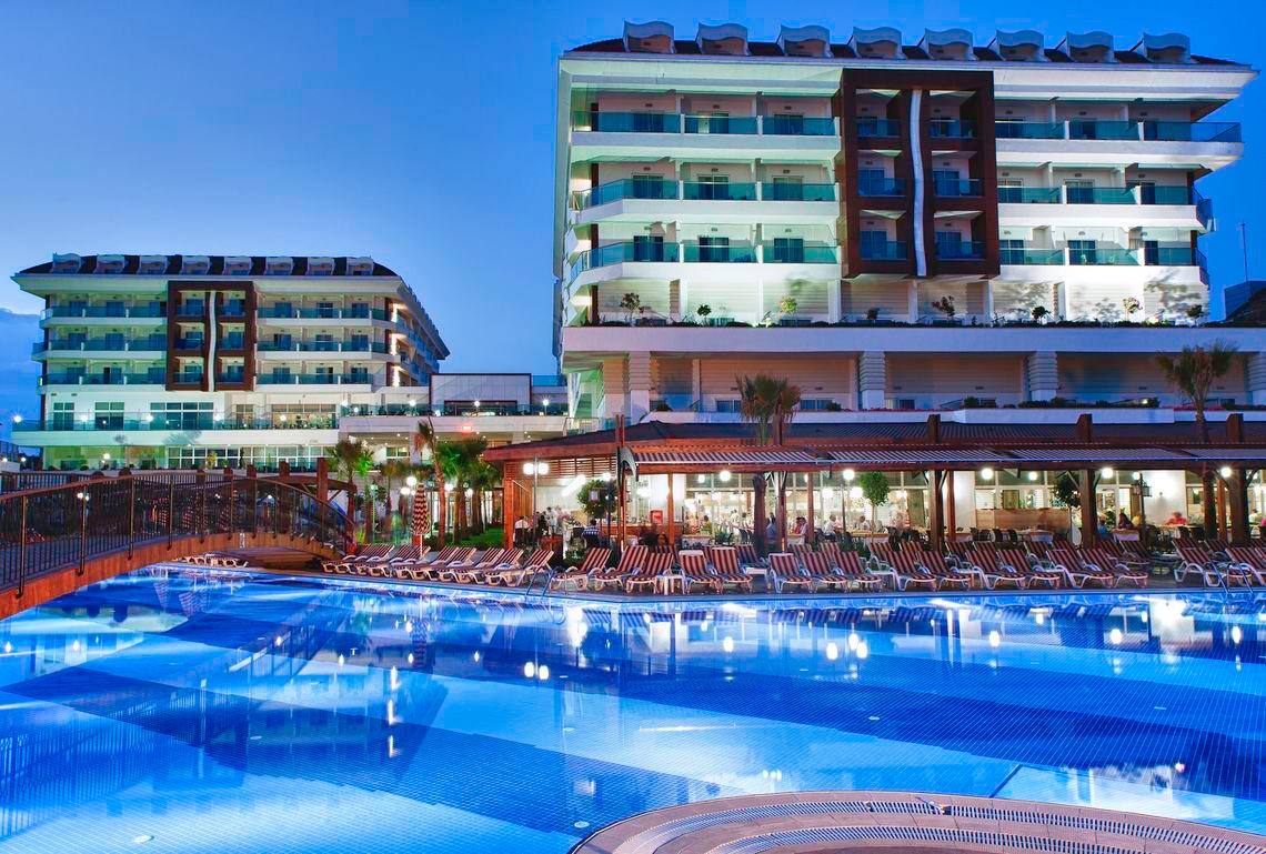 Außenbereich des Adalya Ocean Deluxe Hotels mit Swimmingpool und Lounge-Bereich bei Nacht