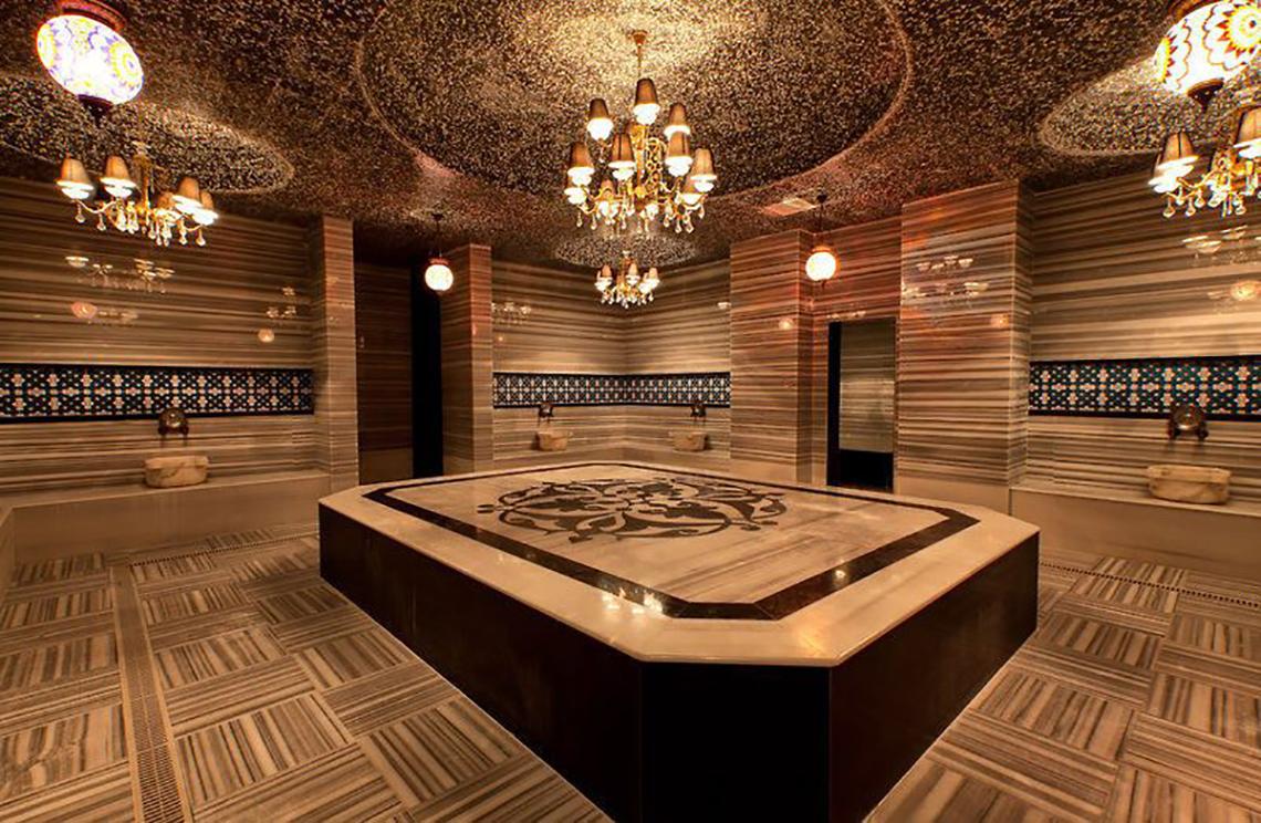 Innenbereich der Sauna im Adalya Ocean Deluxe Hotel mit Marmorboden und dekorativen Kronleuchtern.