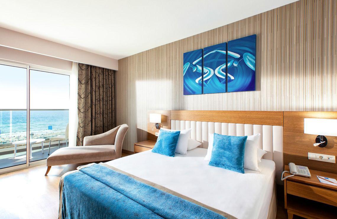 Hotelzimmer im Adalya Ocean Deluxe mit Blick auf das Meer von einer großen Glastür aus.