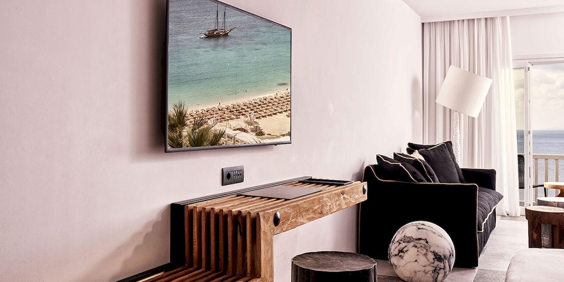 Ein Hotelzimmer mit Fernseher an der Wand und Meerblick.