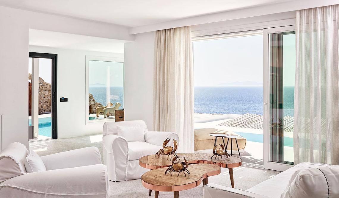 Innenraum des Royal Myconian Resorts mit Blick auf das Meer und eine Terrasse.
