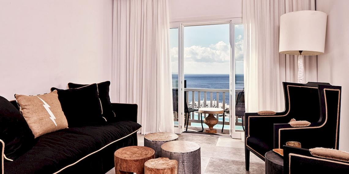 Innenbereich des Royal Myconian Resorts mit Loungebereich, Sofa, Tisch und Meerblick