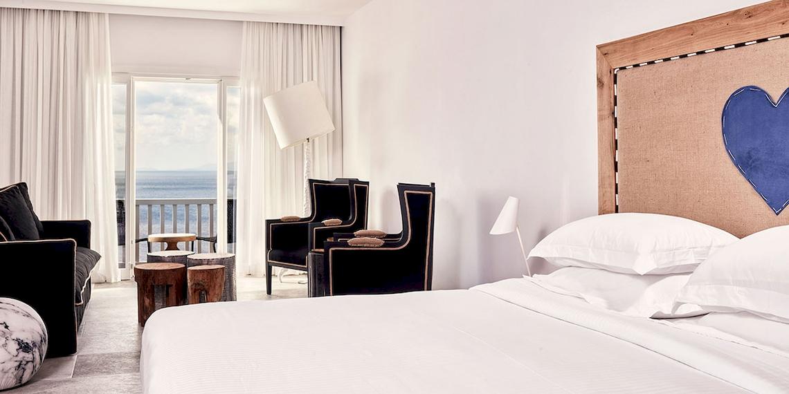 Zimmer im Royal Myconian Resort mit Blick auf das Meer und modernem Interieurdesign.