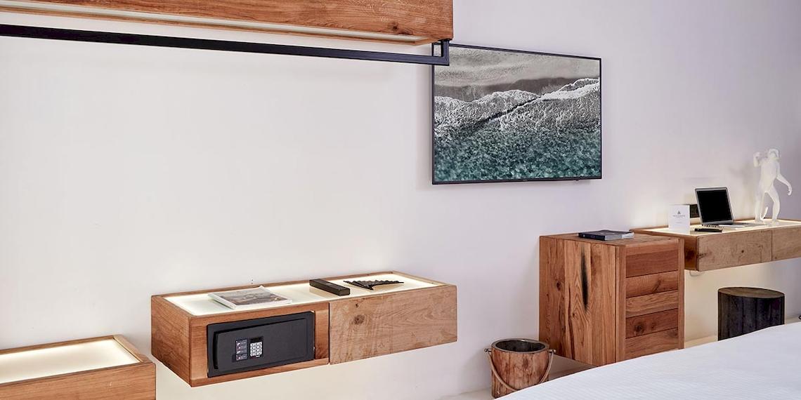 Inneneinrichtung eines Zimmers im Royal Myconian Resort mit Holzmöbeln, Flachbildfernseher, Schreibtisch und Laptop