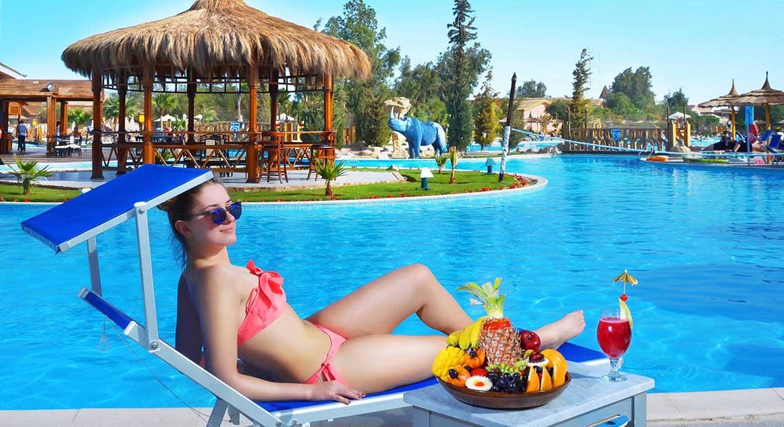 Eine Frau in einem Bikini liegt auf einem Liegestuhl am Pool des Pickalbatros Jungle Aqua Park Resorts.