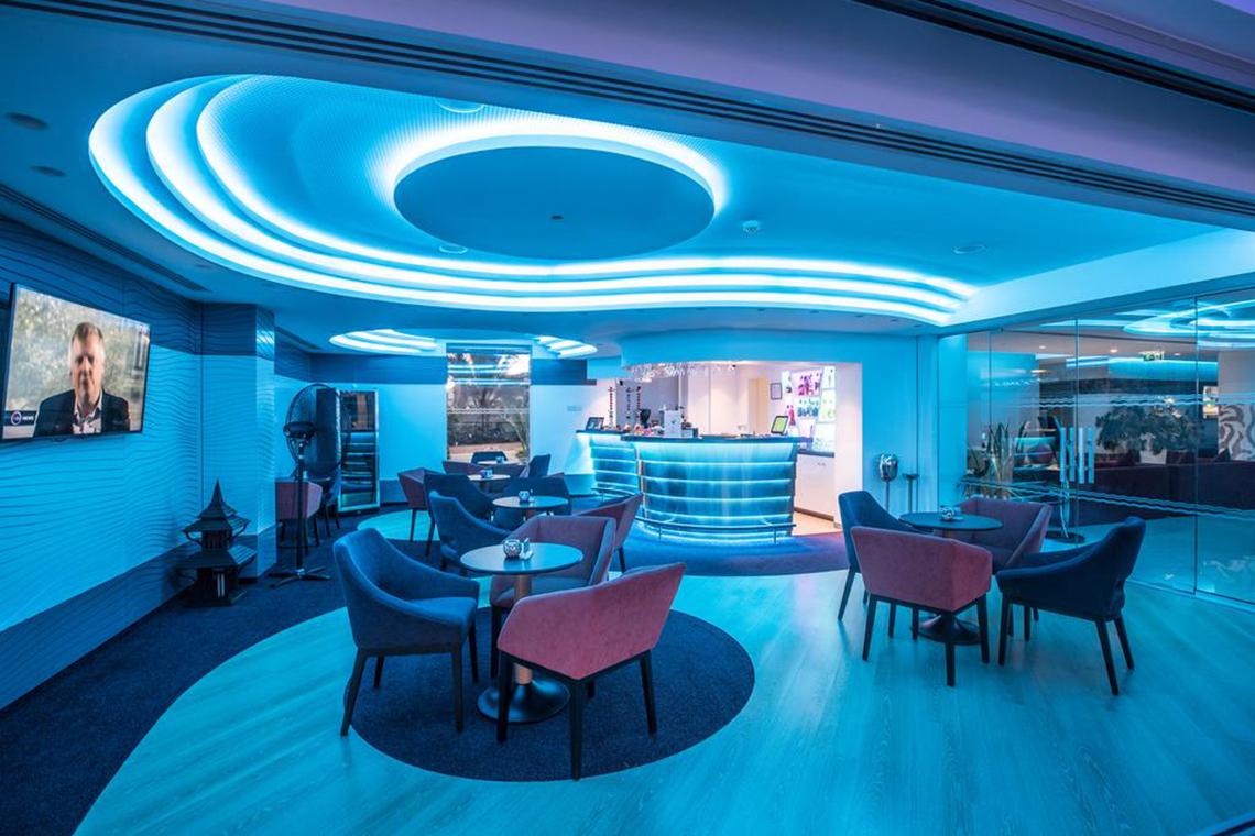 Lobby des Vassos Nissi Plage Hotels mit blauer Beleuchtung und modernen Möbeln.