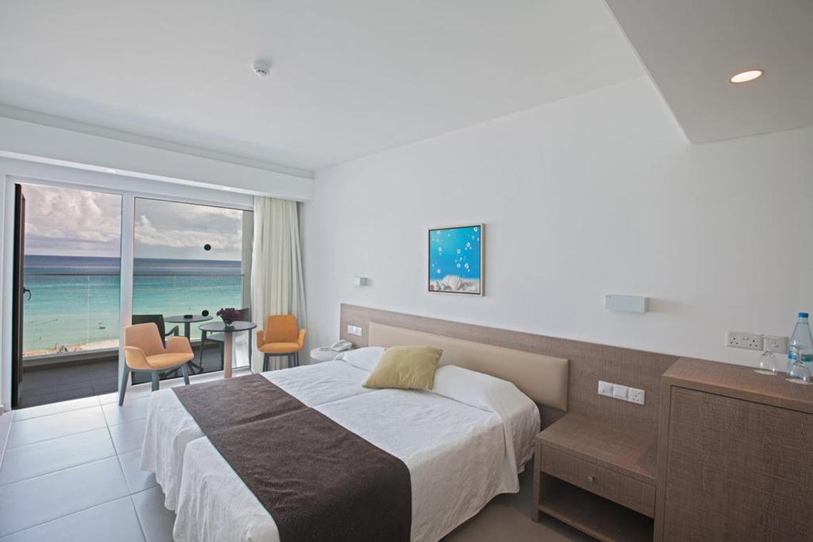 Doppelzimmer im Vassos Nissi Plage Hotel mit Meerblick, modernes Design und Balkonzugang.
