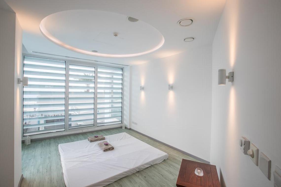 Innenansicht eines Zimmers im Vassos Nissi Plage Hotel mit einem Bett und großen Fenstern.