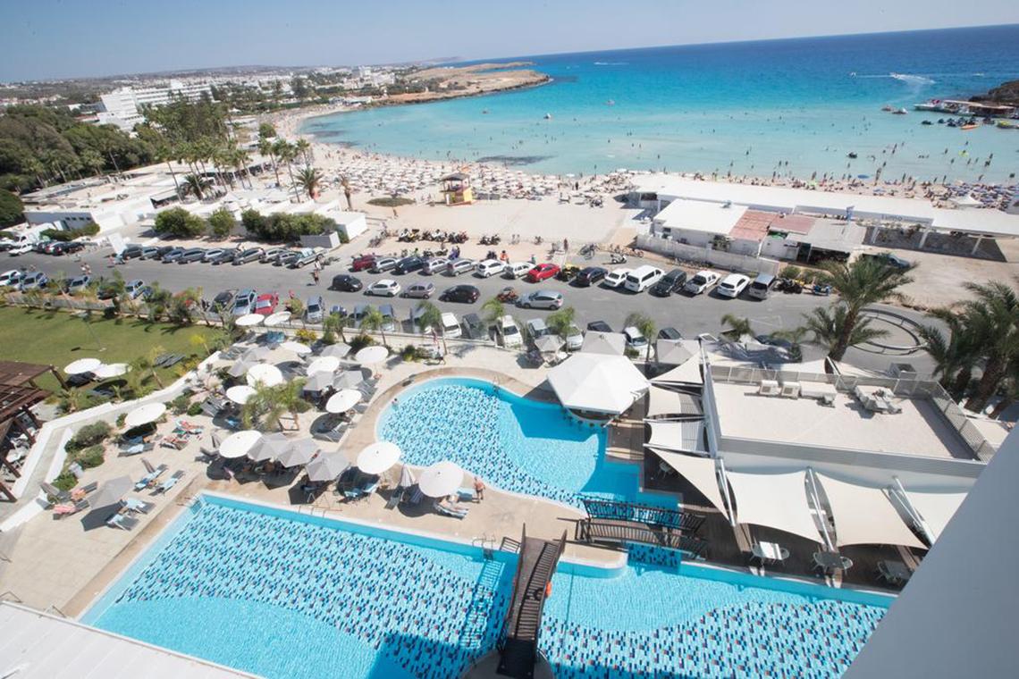Luftaufnahme des Vassos Nissi Plage Hotels mit Blick auf den Pool, den Parkplatz und den Strand