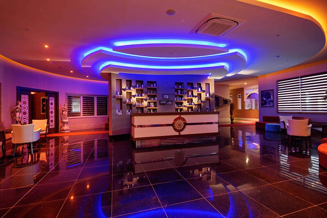 Empfangsbereich des Crystal Sunset Luxury Resort & Spa mit moderner Einrichtung und violetten Beleuchtung.