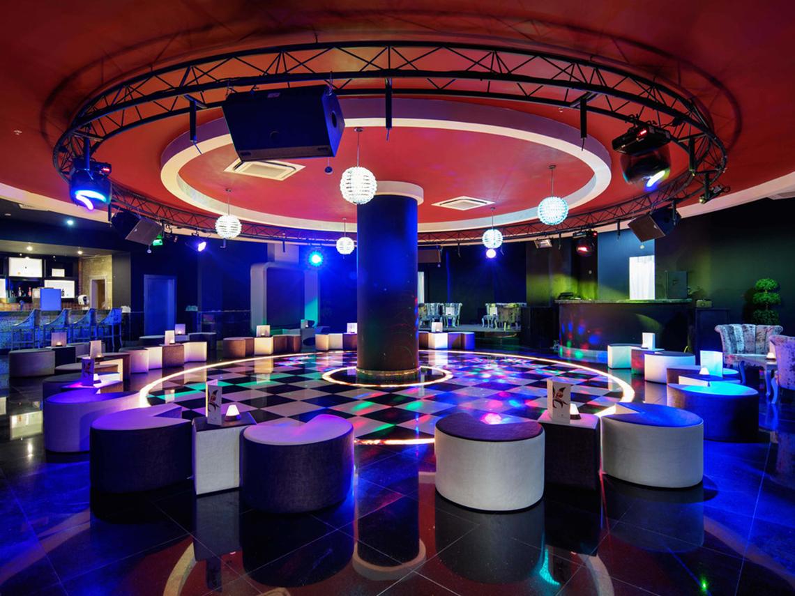 Disco-Raum im Crystal Sunset Luxury Resort & Spa mit bunten Lichtern und Möbeln.