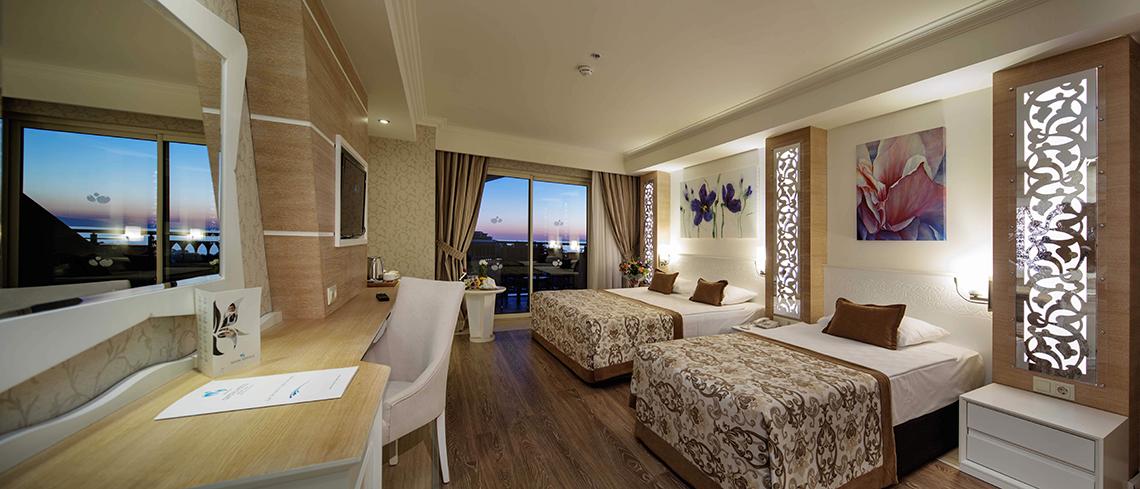 Doppelzimmer im Crystal Sunset Luxury Resort & Spa mit zwei Betten, Schreibtisch und Aussicht auf die Stadt.