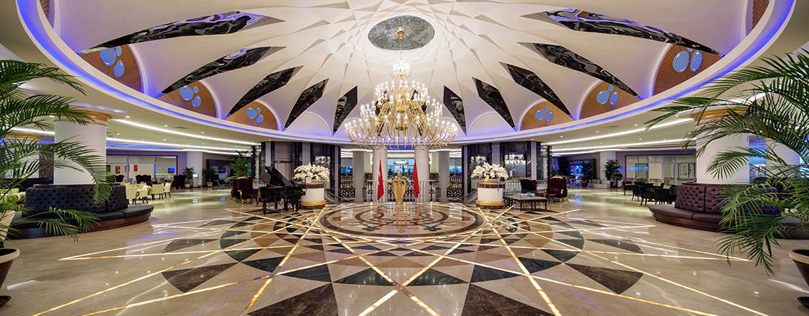 Foyer im Crystal Sunset Luxury Resort & Spa mit großem Kristallleuchter, Marmorboden und dekorativen Elementen.