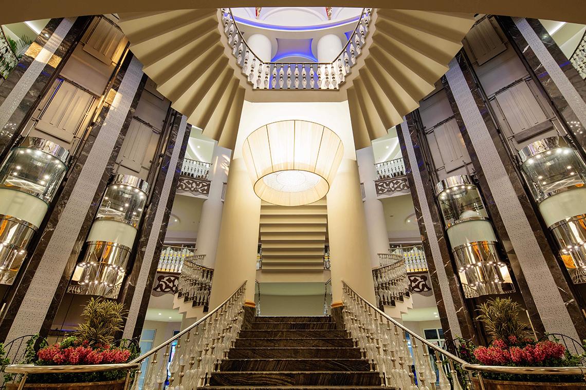 Innenansicht der Lobby im Crystal Sunset Luxury Resort & Spa mit Marmortreppen und Aufzügen.