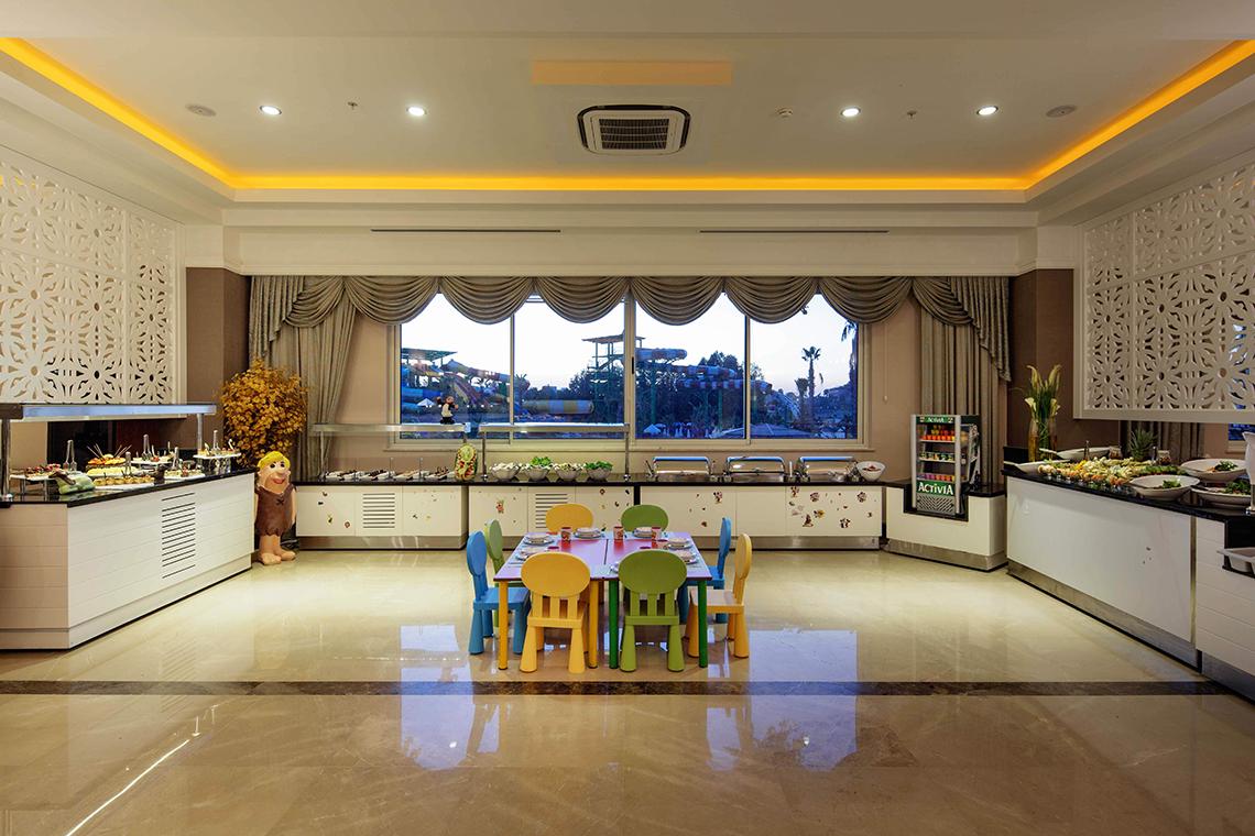 Kindertisch im Crystal Sunset Luxury Resort & Spa mit bunten Stühlen und Ausblick auf den Wasserpark.