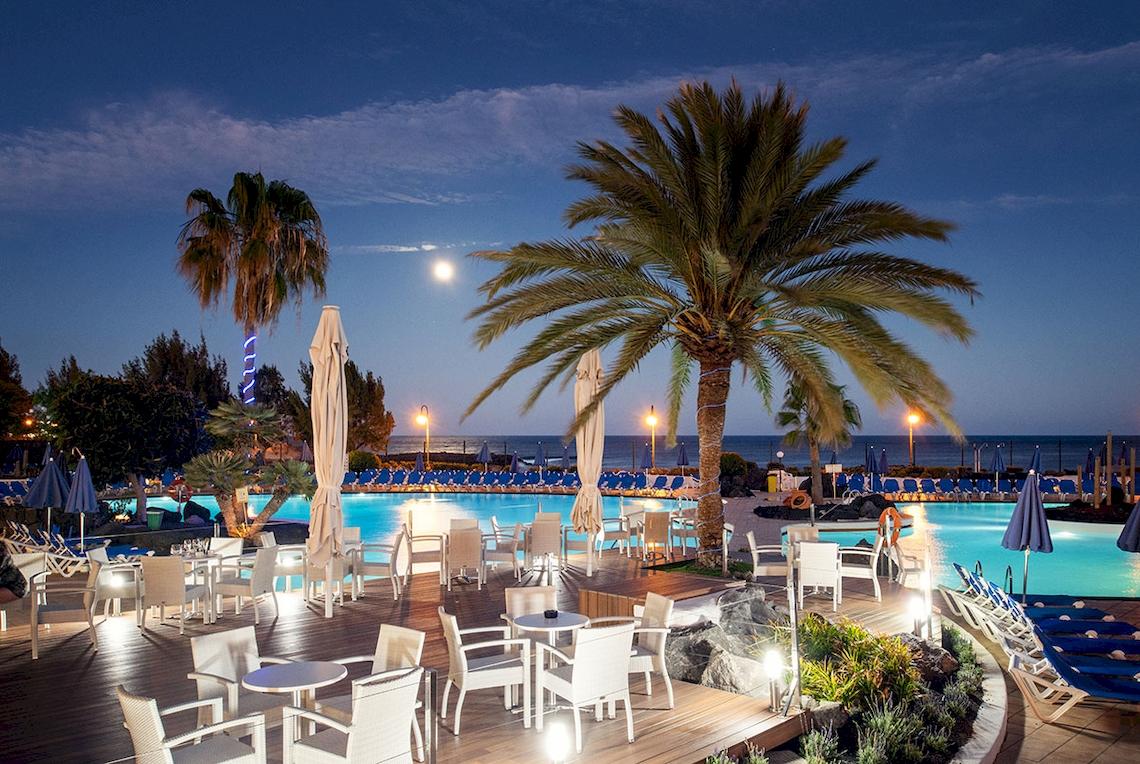 Außenpool des Grand Teguise Playa Hotels bei Nacht mit beleuchteten Tischen und Stühlen