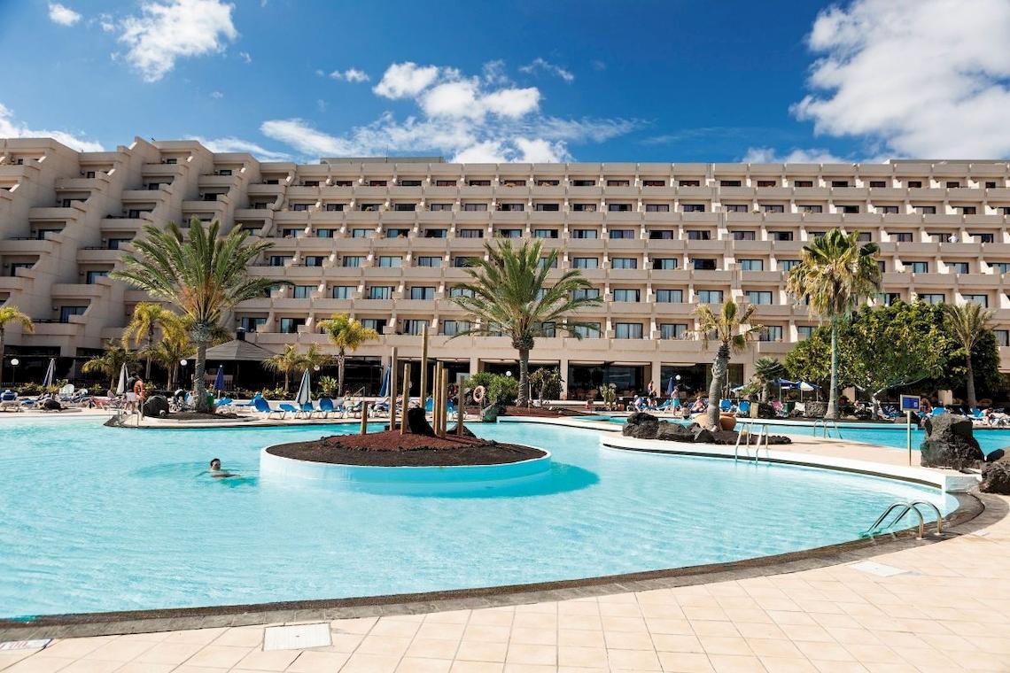 Außenbereich des Grand Teguise Playa Hotels mit Swimmingpool und Liegestühlen.