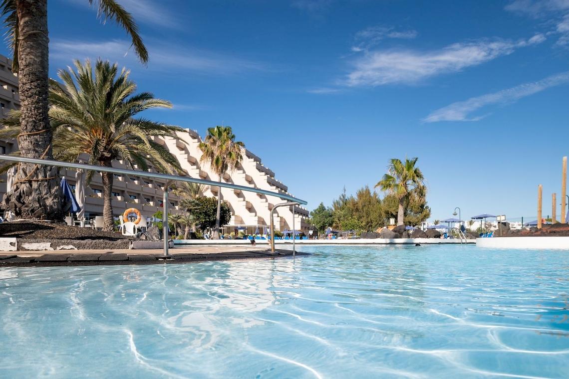 Außenpool des Grand Teguise Playa Hotels mit blauem Wasser und Palmen