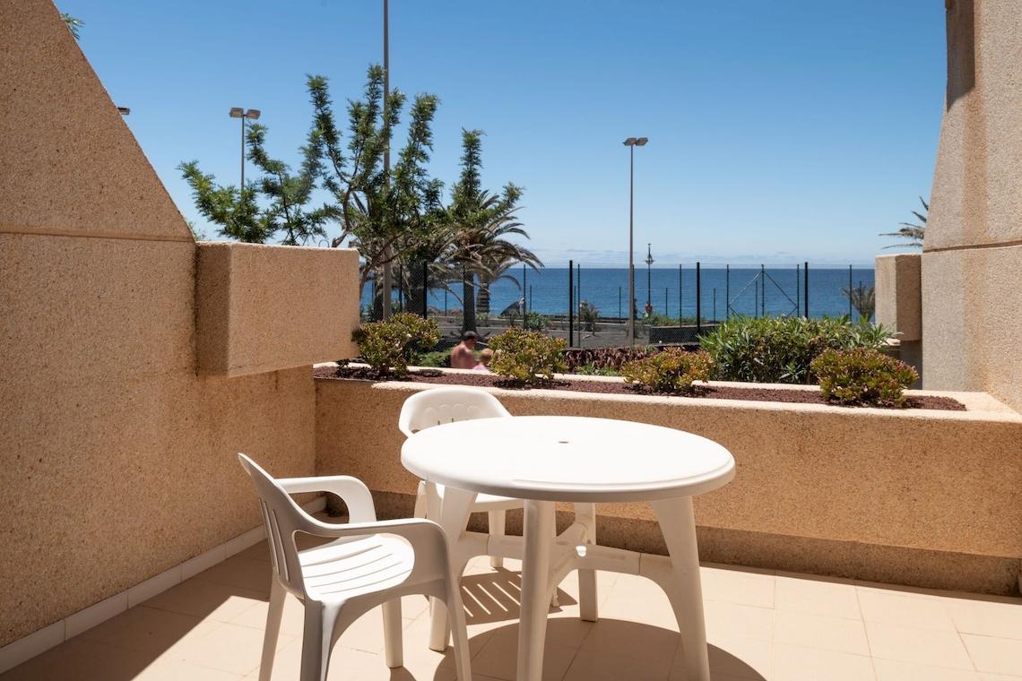 Balkon des Grand Teguise Playa Hotels mit Tisch, Stühlen und Meerblick.
