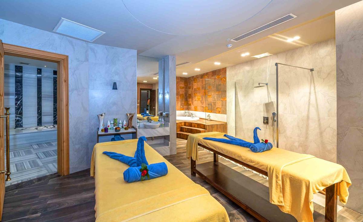 Massageraum im Sidemarin Kirman Premium Hotel mit zwei Liegen und blauen Handtüchern.