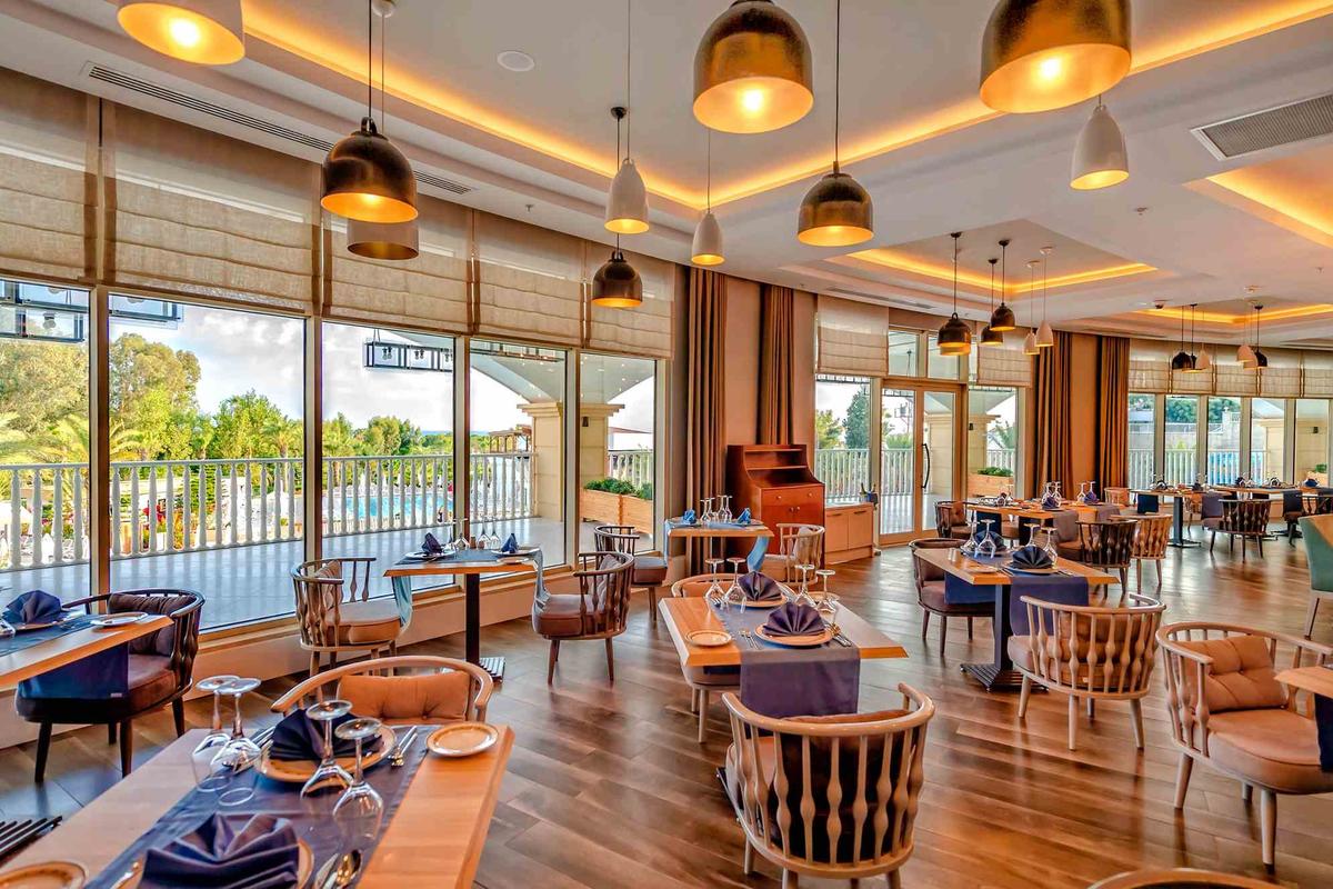 Restaurant im Sidemarin Kirman Premium Hotel mit vollen Tischen und Blick auf den Pool.