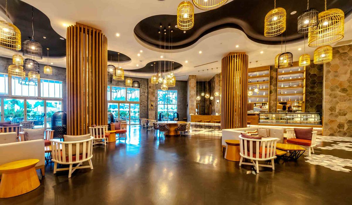 Innenbereich des Sidemarin Kirman Premium Hotels mit Lounge-Stühlen, Tischen und gelben Pendelleuchten.