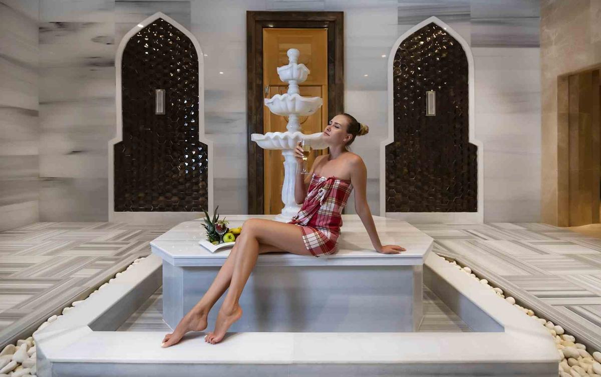 Eine Dame sitzt am Brunnen im Sidemarin Kirman Premium Hotel.