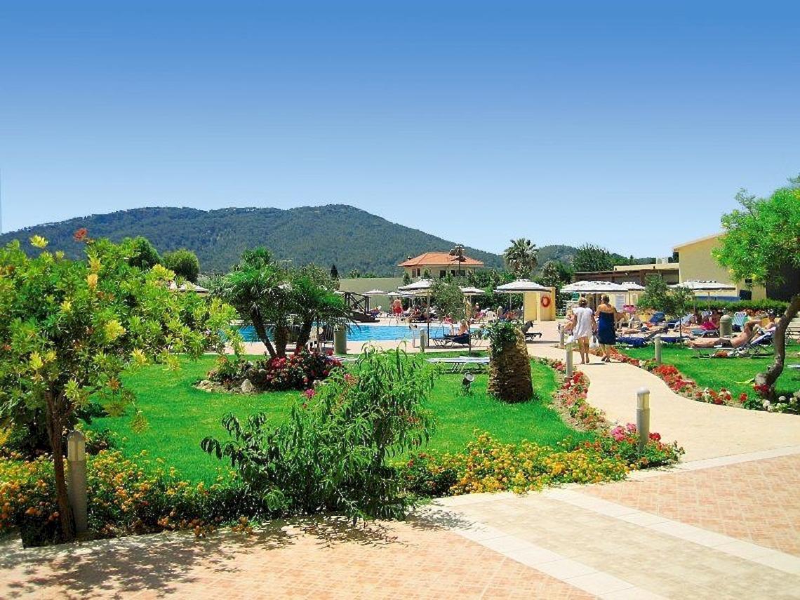 Außenbereich des Electra Palace Rhodes Hotels mit Garten, Pool und Berg im Hintergrund.