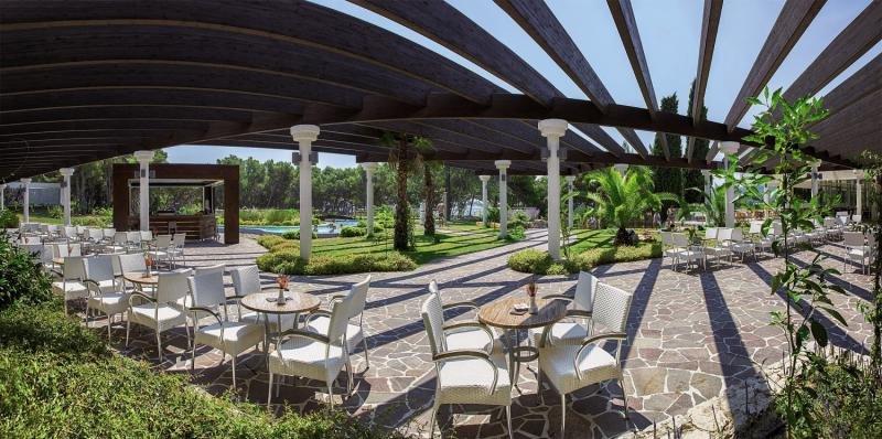 Außenbereich des Niko Hotels mit Pergola, Tischen und Stühlen im Freien.