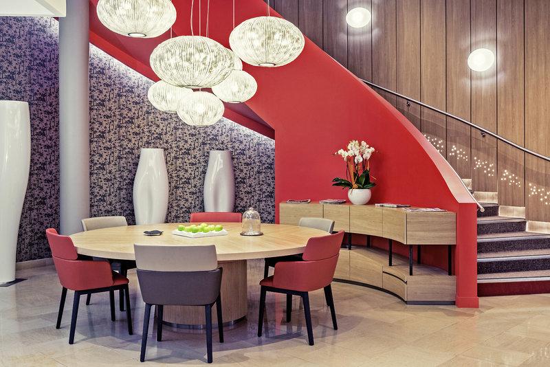 Innenbereich des Mercure Paris Montmartre Sacré-Coeur mit rundem Tisch, roten Stühlen und roten Treppen