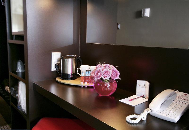 Einrichtung im Zimmer des Mercure Paris Montmartre Sacré-Coeur Hotels, inklusive Telefon, Schreibtisch und Blumenvase.
