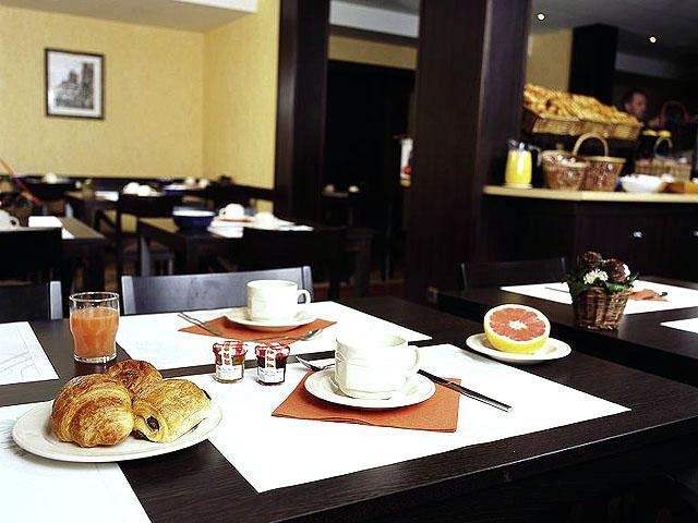 Frühstückstisch im Mercure Paris Montmartre Sacré-Coeur Hotel mit Croissants, Getränken und Früchten.