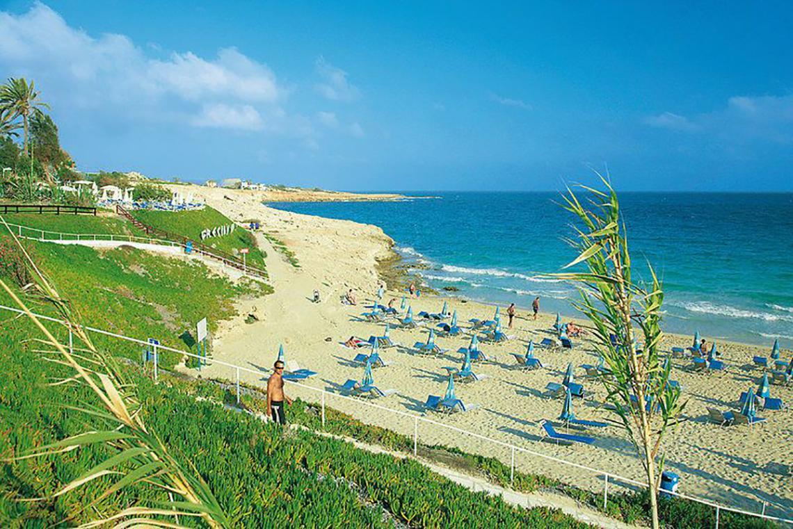 Strandansicht des Napa Mermaid Hotel & Suites mit vielen Liegestühlen und Besuchern.