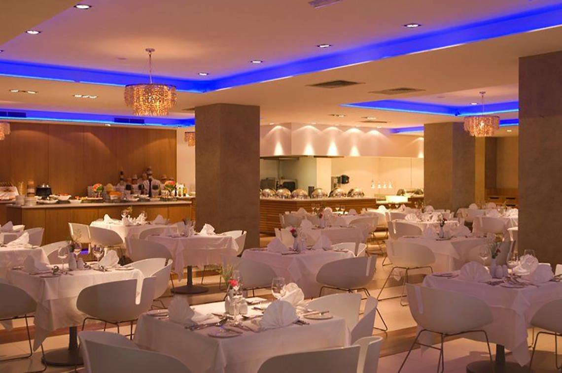 Restaurant des Napa Mermaid Hotel & Suites mit blauen Beleuchtung und weißen Tischen.