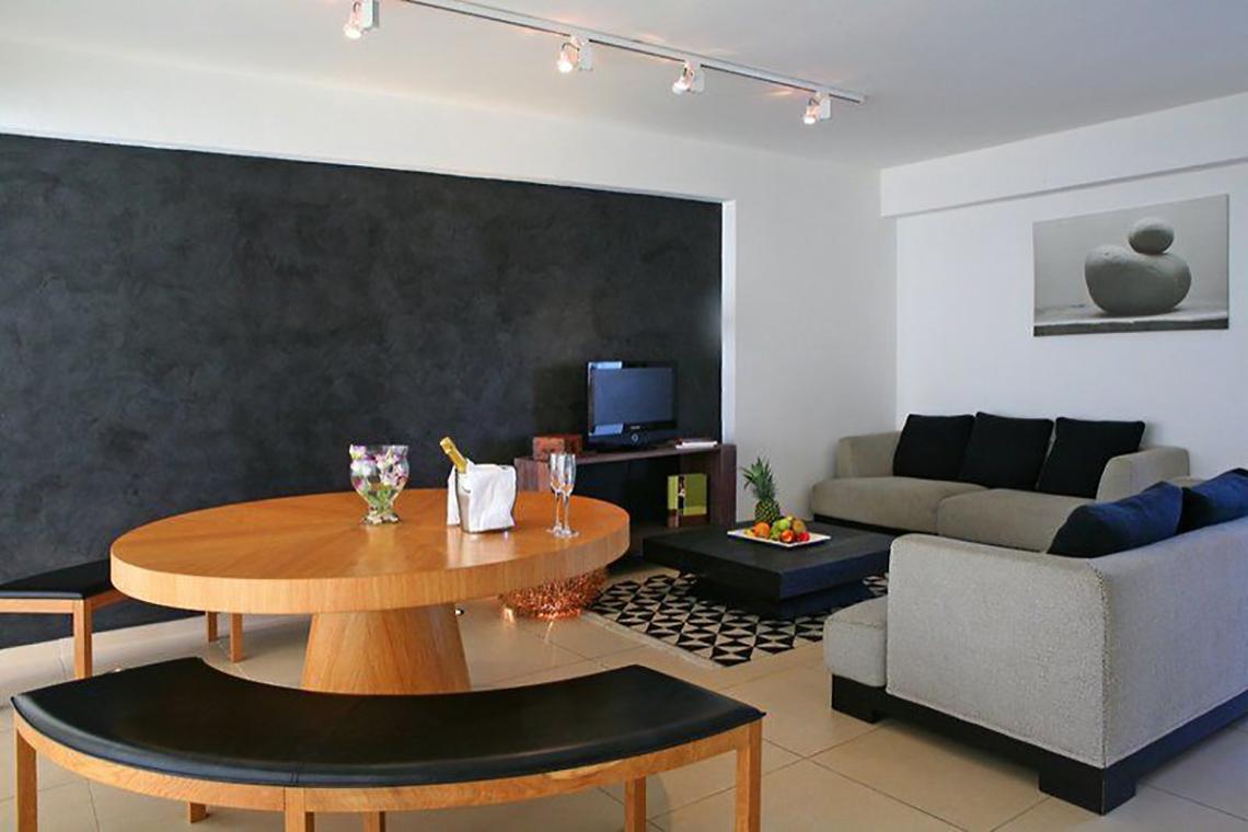 Wohnzimmer im Napa Mermaid Hotel & Suites mit grauem Sofa, Couchtisch und Tisch