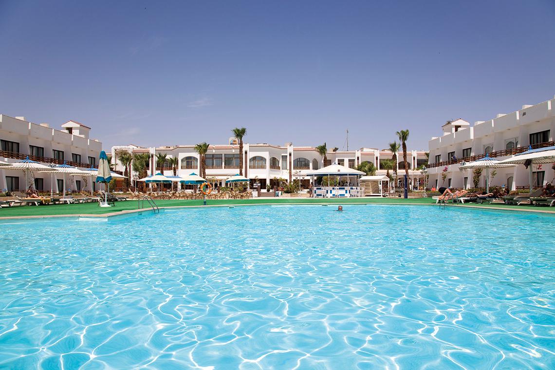 Außenpool des Grand Hotel Hurghada mit Sonnenliegen und Schirmen.