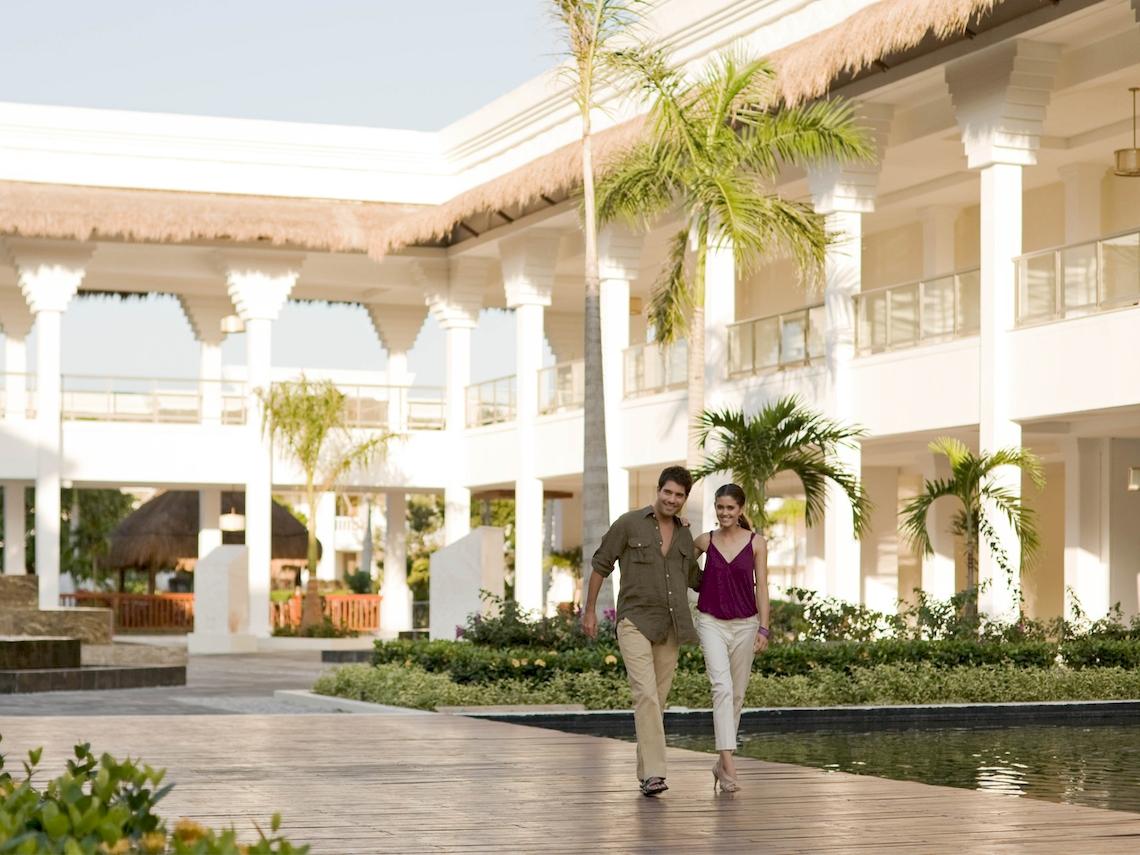 Ein Mann und eine Frau gehen vor dem Grand Sunset Princess All Suites Resort.