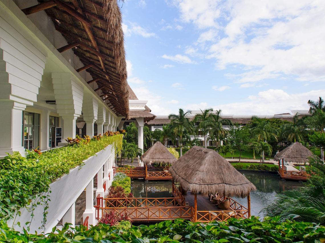 Außenansicht des Grand Sunset Princess All Suites Resorts mit Gebäuden, Dächern und einem See.