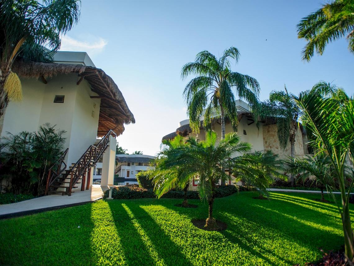 Außenansicht des Grand Sunset Princess All Suites Resorts mit Gebäuden, Palmen und Rasen
